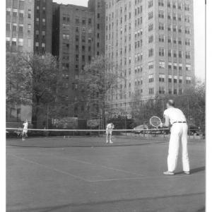 Staff members playing tennis, about 1960